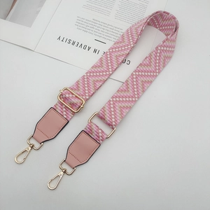 Détail d'une bandoulière tissée rose avec crochets dorés et finitions en similicuir