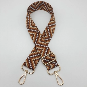 Detail of adjustable geometric woven bag strap with golden metal spring hooks