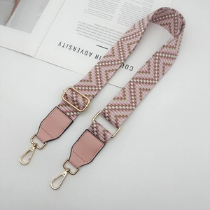 Détail de la bandoulière tissée rose et blanche avec boucles dorées et attaches en cuir