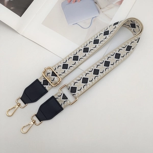 Detail of wide woven strap with geometric diamond patterns and gold metal lobster clasps
