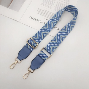 Détail d'une bandoulière tissée bleue avec embouts en cuir et boucle en métal doré