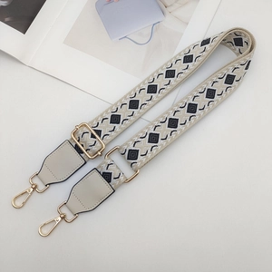 Close-up of geometric patterned wide crossbody bag strap with gold metal buckles