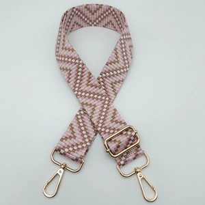 Detail showing pink and brown geometric woven bag strap with golden metal swivel hooks
