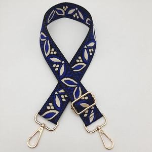 Detail view of the blue and beige embroidered guitar strap with golden metal swivel hooks