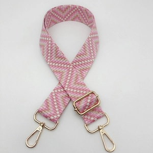 Detail of adjustable wide woven shoulder strap with pink geometric jacquard and gold metal hooks