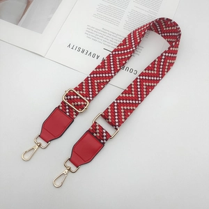 Détail de la bandoulière tissée rouge avec boucle dorée réglable et mousquetons pivotants