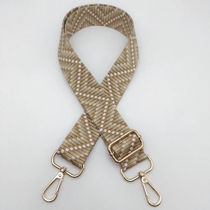 Close-up of khaki and white geometric woven strap with polished gold metal swivel hooks