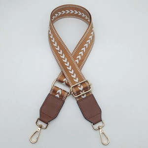 Detail of caramel nylon bag strap with white V-pattern and gold metal swivel hook
