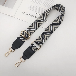 Détail de la bandoulière réglable à motifs géométriques noirs et blancs avec crochets dorés