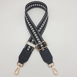 Detail showing black and white geometric canvas strap with gold metal buckle and leather ends