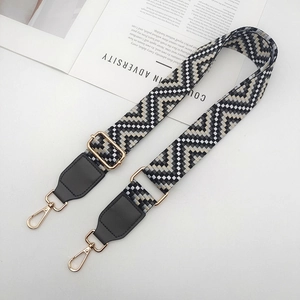 Détail de la sangle tissée géométrique noire et blanche avec crochets en métal doré