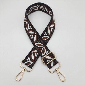 Close-up of adjustable jacquard guitar strap with leaf pattern and gold metal hooks