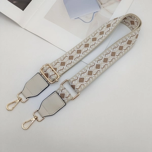 Close-up of geometric jacquard woven strap with golden lobster clasps and grey leather ends