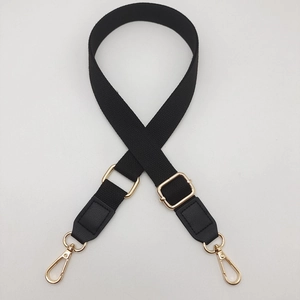 Detail of black woven shoulder strap with gold metal buckles and adjustable slider