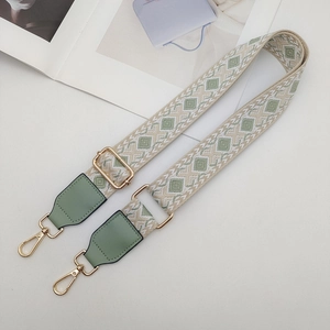 Detail of adjustable geometric ethnic strap with golden metal clasps and green leather trim