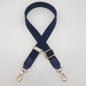 Detail of navy blue nylon bag strap with gold metal buckle and leather ends