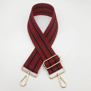 Detail of red and black geometric woven bag strap with light gold metal lobster clasps