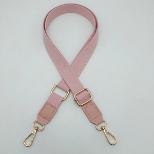 Detail view of adjustable light pink cotton webbing strap with gold metal hardware hooks
