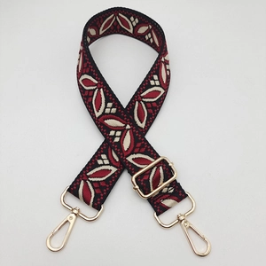 Close-up of wide embroidered guitar-style bag strap with gold metal hooks and floral pattern