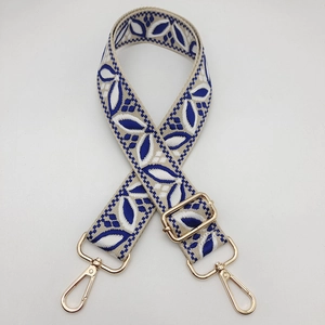 Detail of adjustable woven guitar-style shoulder strap with blue leaf pattern and gold hardware