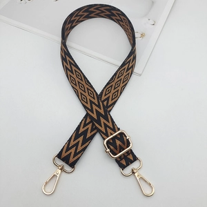 Detail of adjustable woven bag strap with geometric patterns and gold metal buckles