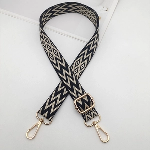Detail of adjustable embroidered bag strap with black geometric patterns and gold clips