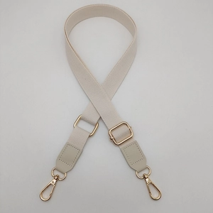 Detail of adjustable off-white woven shoulder strap with gold-tone metal buckles
