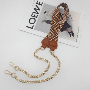 Detail of woven bag strap with orange V-pattern, leather ends and gold metal chain