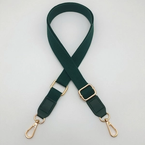 Detail of dark green cotton webbing bag strap with adjustable gold hardware and swivel hooks