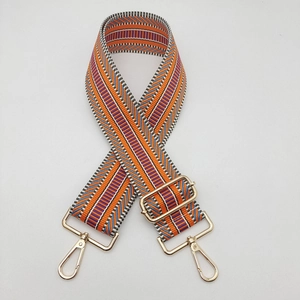 Detail of colorful ethnic geometric woven bag strap with gold metal hooks and adjustable buckle
