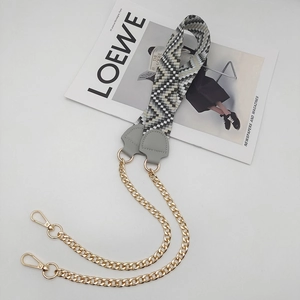 Detail of grey geometric woven shoulder strap with gold chains and lobster clasps