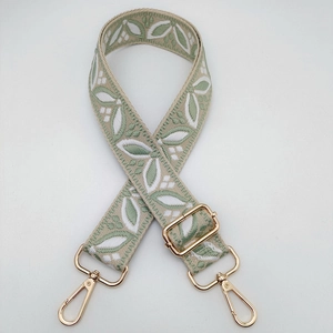 Adjustable jacquard woven bag strap with green leaf patterns and gold metal hooks