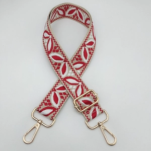 Detail of red and white floral embroidered guitar style strap with gold metal lobster clasps