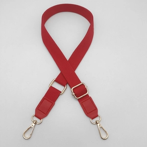 Detail of red canvas strap with gold metal buckle and leather reinforced ends for bags