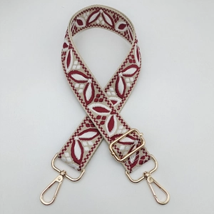 Close-up of ethnic woven floral guitar style bag strap with gold metal lobster clasps