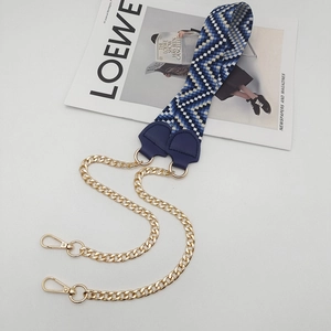 Detail of the woven geometric pattern shoulder strap with golden metal chains and lobster clasp