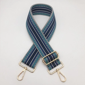 Detail of adjustable wide woven shoulder strap with ethnic pattern and gold metal hardware