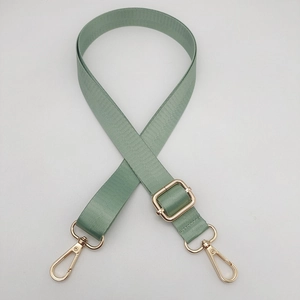 Detail of adjustable light green nylon shoulder strap with polished gold-tone metal hooks