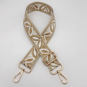 Close-up of ethnic style embroidered strap with gold metal hooks and leaf pattern detail