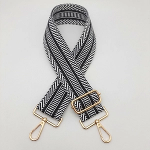Detailed view of black and white woven strap with golden adjustable buckle and swivel hooks