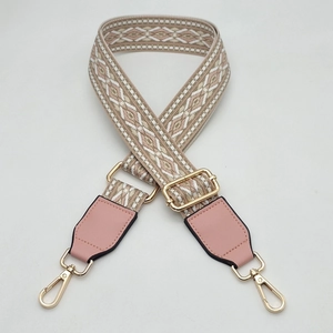 Detail of wide woven strap with pink leather accents and golden metal hardware buckles