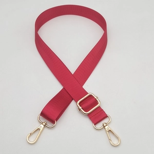 Detail of rose red nylon bag strap with golden metal lobster clasps and buckle