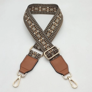 Detail of bohemian geometric woven bag strap with brown leather ends and gold metal buckle