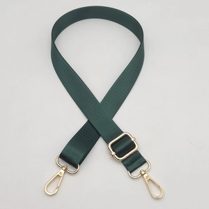 Close-up of forest green nylon bag strap with polished gold metal lobster clasps