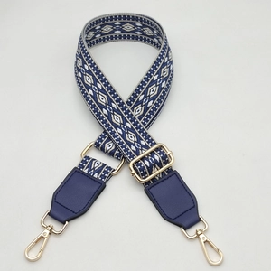 Close-up of geometric woven strap with navy leather ends and gold metal lobster clasps
