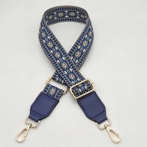 Close-up of adjustable woven shoulder strap with blue geometric pattern and gold hooks