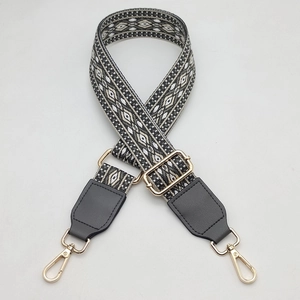 Close-up of geometric pattern crossbody bag strap with golden lobster clasps