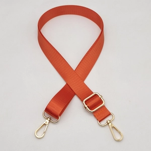Detail of adjustable orange woven bag strap with golden lobster clasps and metal hardware