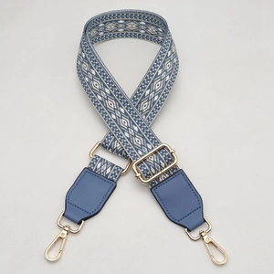 Macro detail of adjustable blue and white geometric woven strap with gold lobster hooks