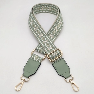 Detail of adjustable geometric woven bag strap with green leather and gold hardware